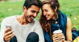 Escort riendo con una mujer, sentados en el parque